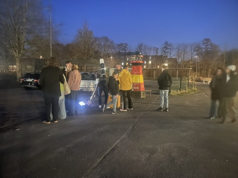 Kinder und Jugendliche beobachten Jupiter durch ein Teleskop
