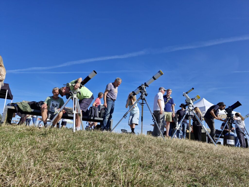 Das Foto zeigt mehrere Teleskope bei der Sonnenbeobachtung und den ersten Besuchern, die einen Blick auf die Sonne werfen wollten.
